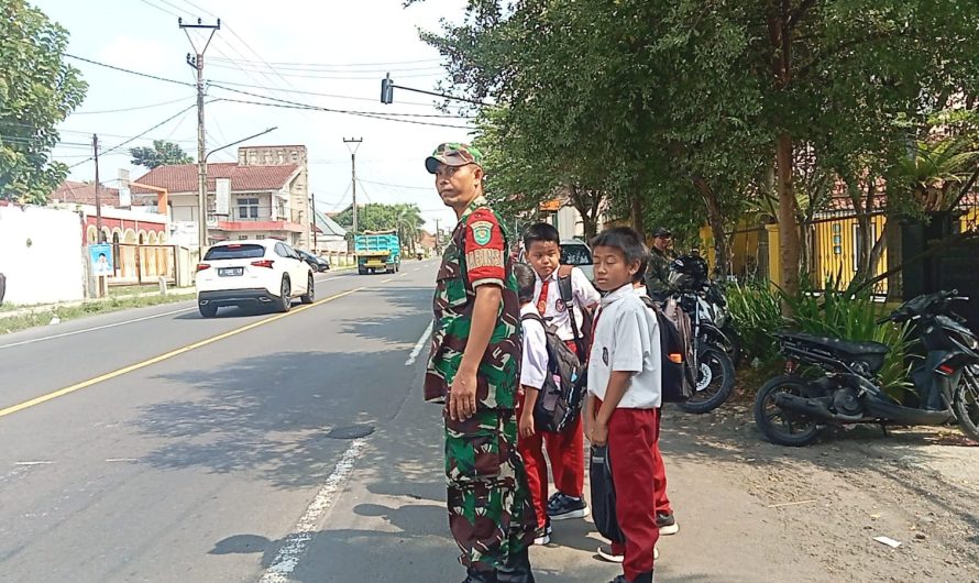 Peduli Keselamatan, Babinsa Koramil 1302/Cikoneng Bantu Seberangkan Anak Sekolah